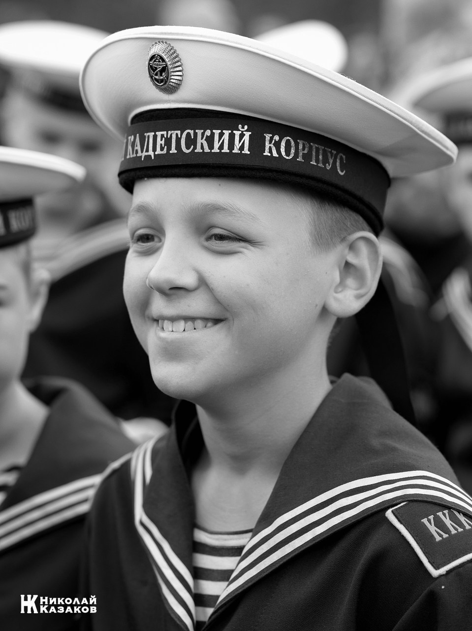 Черно-белый портрет смеющегося воспитанника Кронштадского морского кадетского военного корпуса на построении.