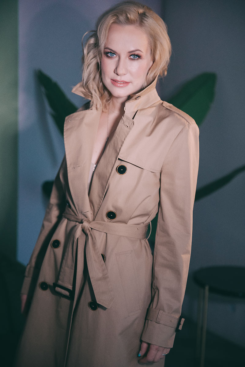 Красивая молодая девушка в бежевом тренче на фотосессии в студии