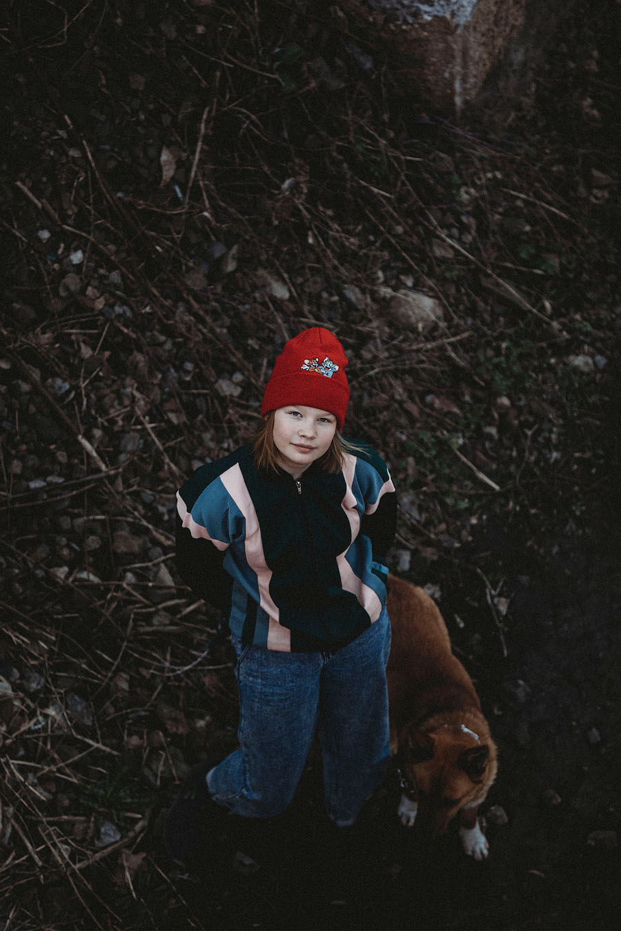 красивая девочка в красной шапке и джинсах гуляет со своей собакой на природе в городе