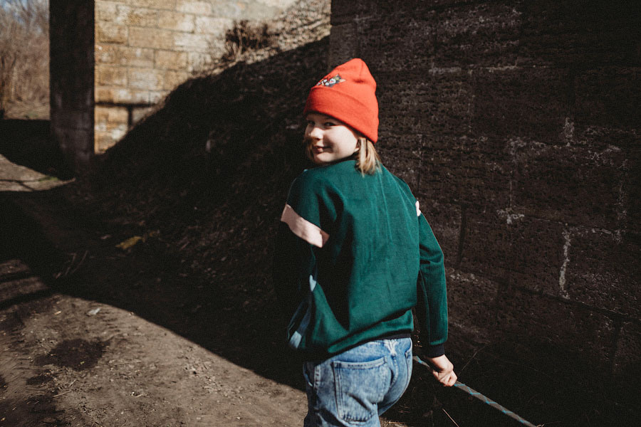 красивая девочка в джинсах и зеленом бомбере гуляет на улице весной