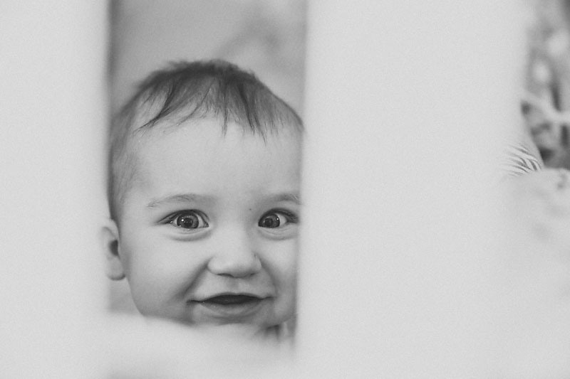 маленький ребенок лежит на кроватки у себя дома и улыбается маме