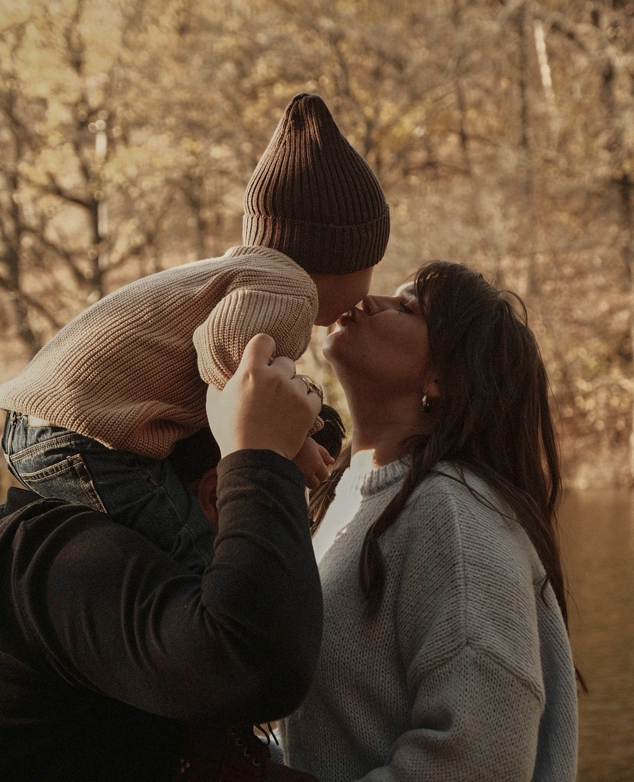 семейная съемка в лесу мама целует сына сидящего на плечах отца 
