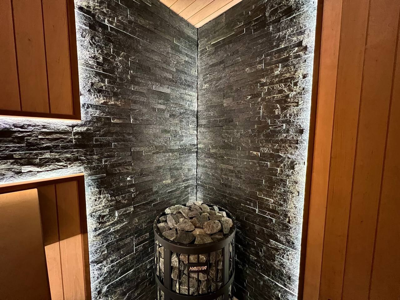 Просторная сауна в Сертолово из термоольхи с интеграцией можжевеловых линий и большого количества натурального камня. SaunaTopMasters