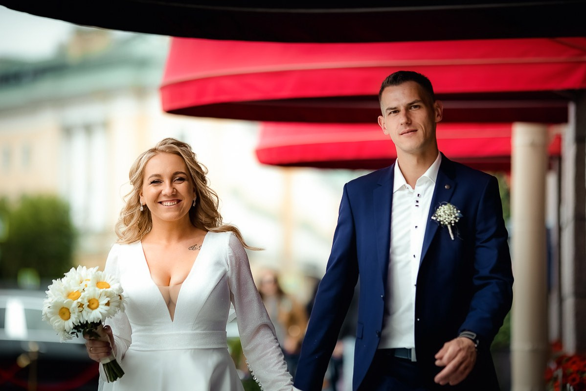 Жених и невеста прогуливаются возле гостиницы "Астория" в Санкт-Петербурге. Горизонтальный поясной кадр.