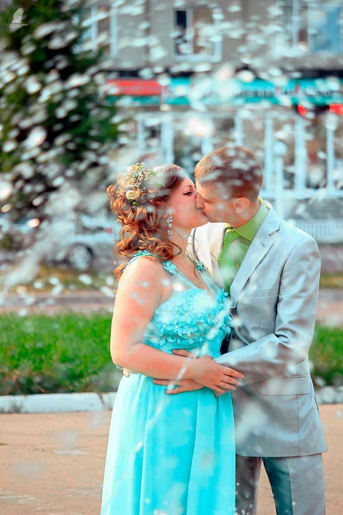 жених целует невесту на фоне городского фонтана