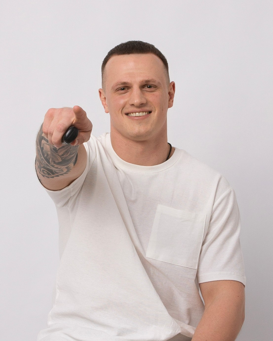 Молодой парень в белой футболке протягивает вперед пульт управления что бы сделать снимок