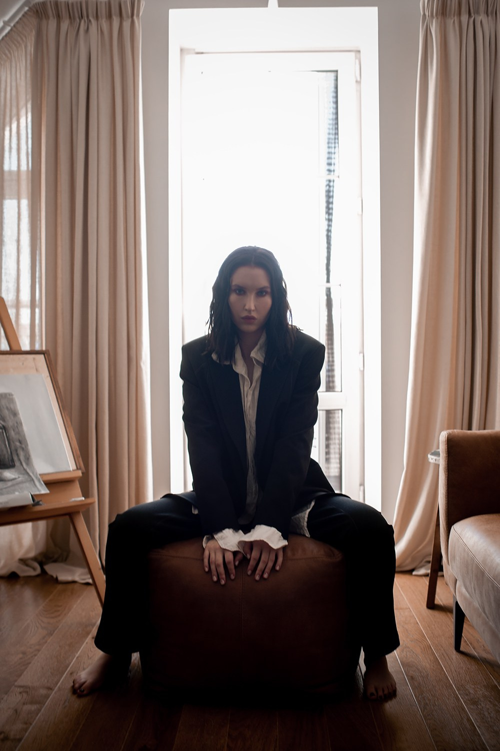 Девушка на фоне окна в пиджаке и в брюках в белой рубашке