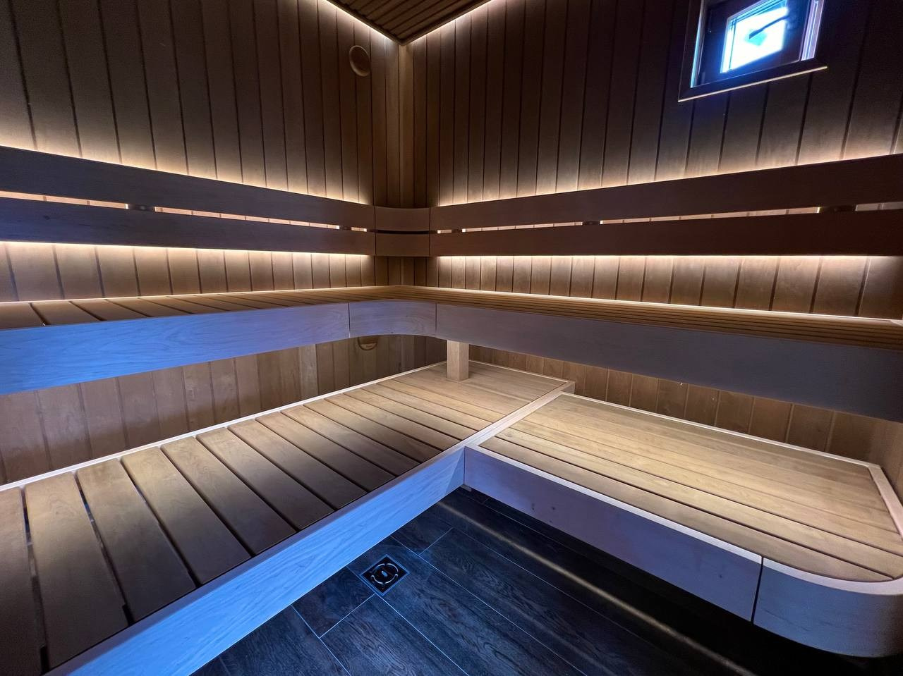 Парная в Колосе по индивидуальному проекту с реечным потолком, плавными линиями радиальных элементов и теплой закарнизной подсветкой. SaunaTopMasters