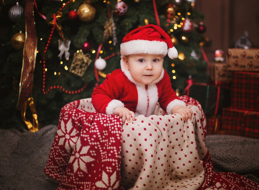 Малыш 1 год в костюме деда Мороза позирует на новогодней фотосессии.