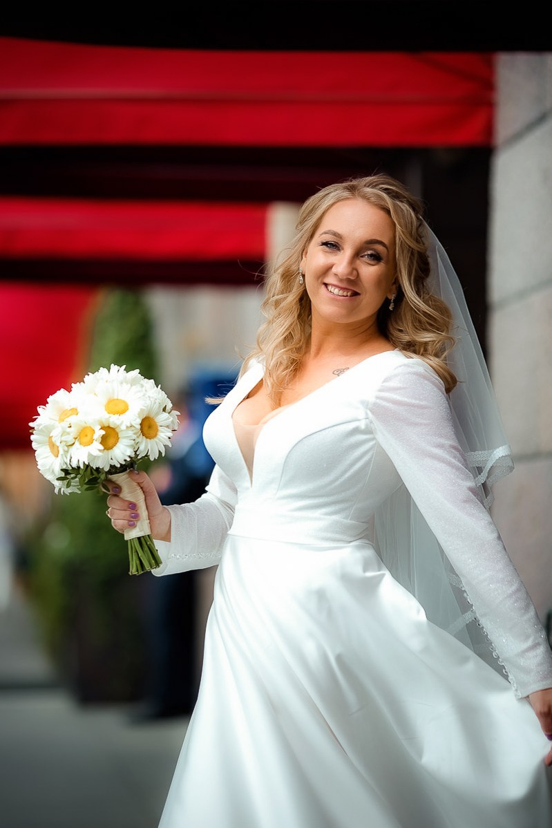 портрет невесты в движении возле гостиницы "Астория" в Санкт-Петербурге. Вертикальный поясной кадр.