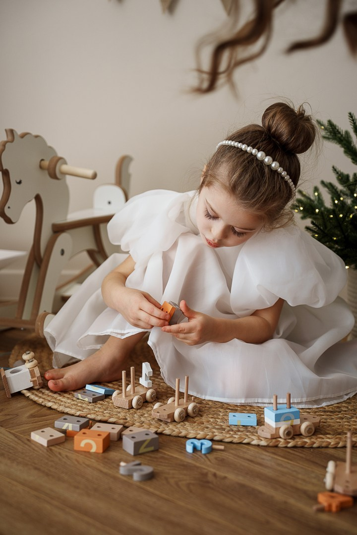 Маленькая принцесса в пышном белом платье играет с игрушками. Детская фотосессия на новогодней локации. Фотограф Едапина Дарья, Новосибирск.