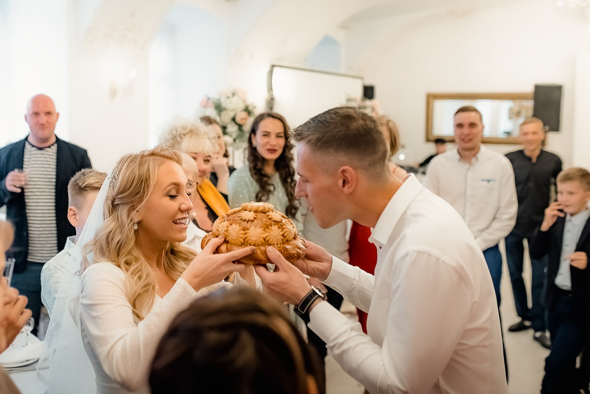 Жених и невеста собираются откусывать хлеб в ресторане в Санкт-Петербурге.  Горизонтальный  поясной кадр.