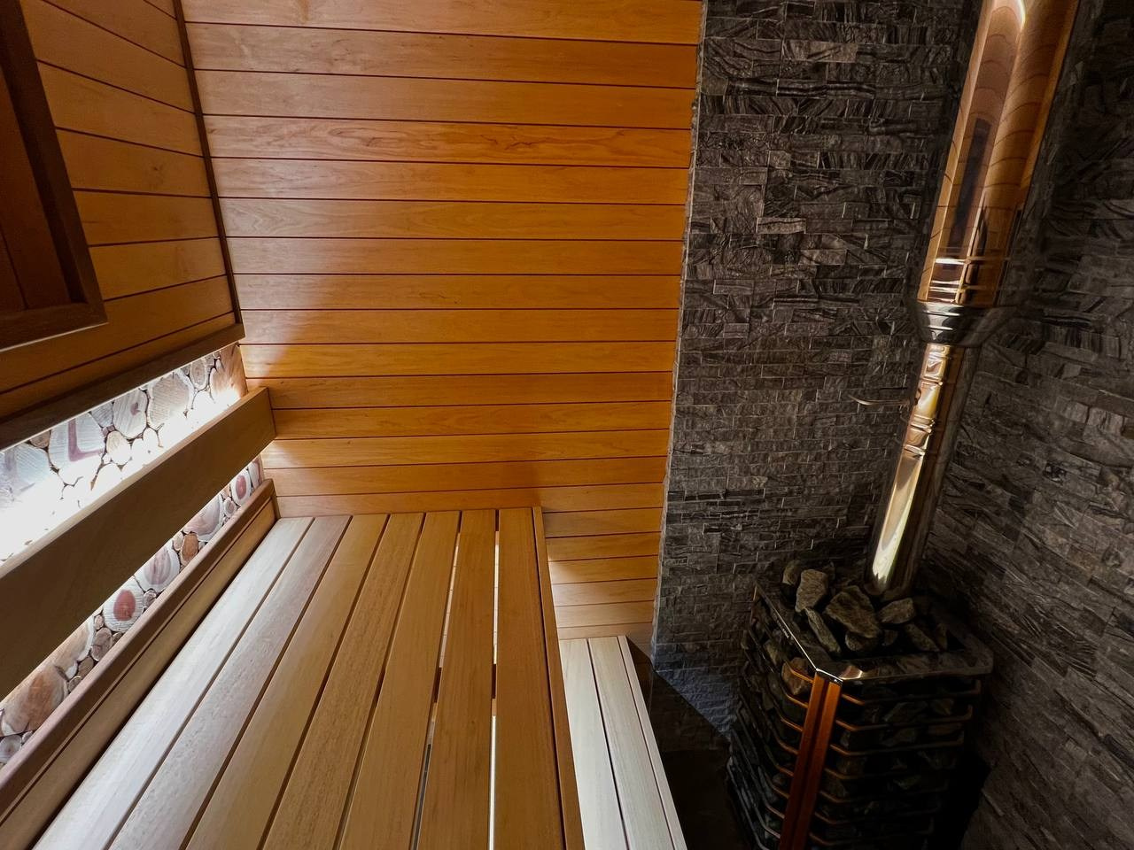 Компактная баня в Терра-Выборгском: светлая ольха в горизонтали и абаш на парящих полках визуально расширяют пространство. SaunaTopMasters