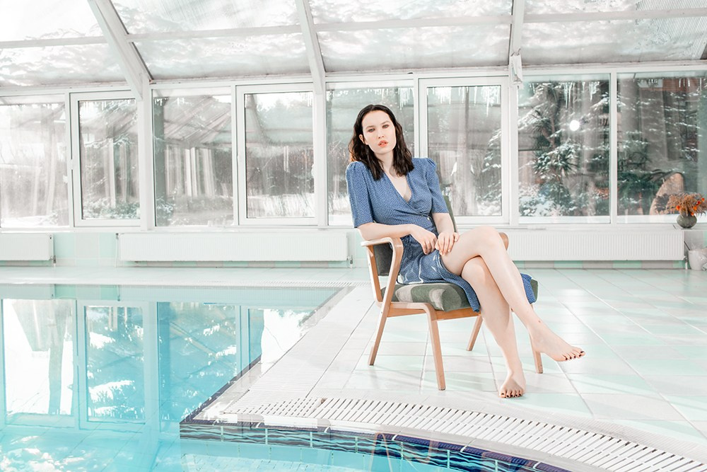 Девушка в синем платье у крытого бассейна