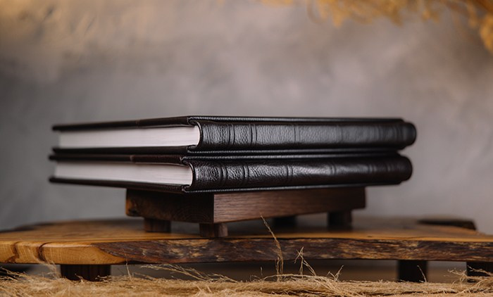 Две кожаные фотокниги ручной работы на подставке из натурального дерева.