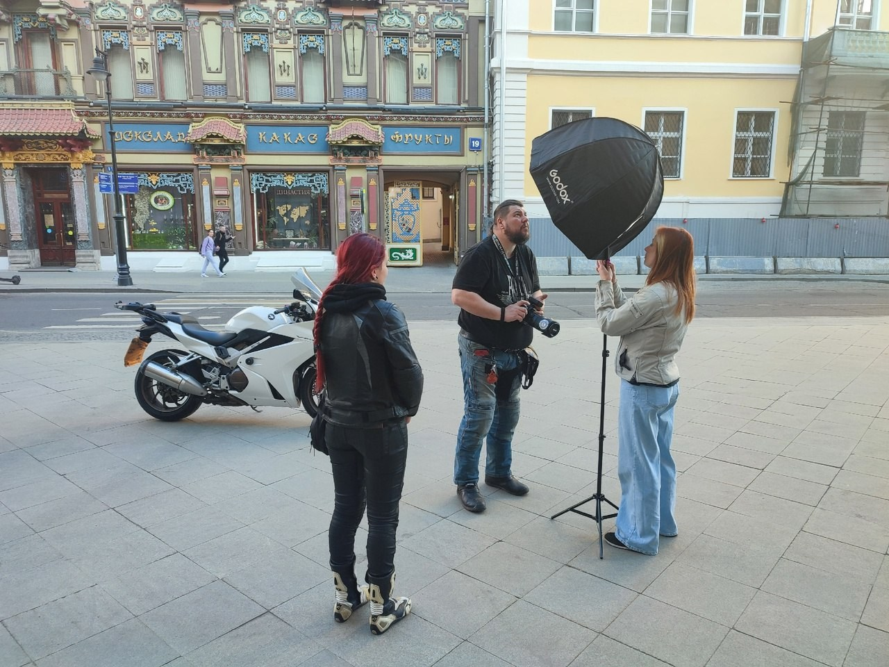 фотограф на съемках проверяет работу вспышки в октабоксе напротив чайного дома в москве