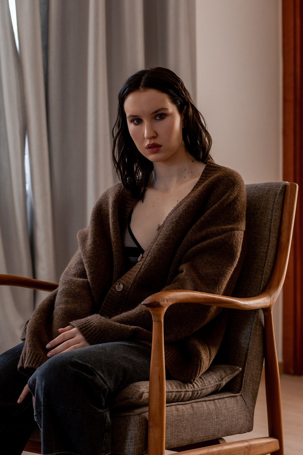 Девушка в свитере на стуле дома