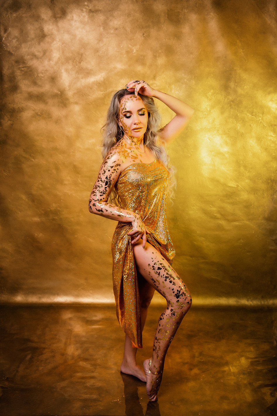 девушка в золоте позирует перед камерой