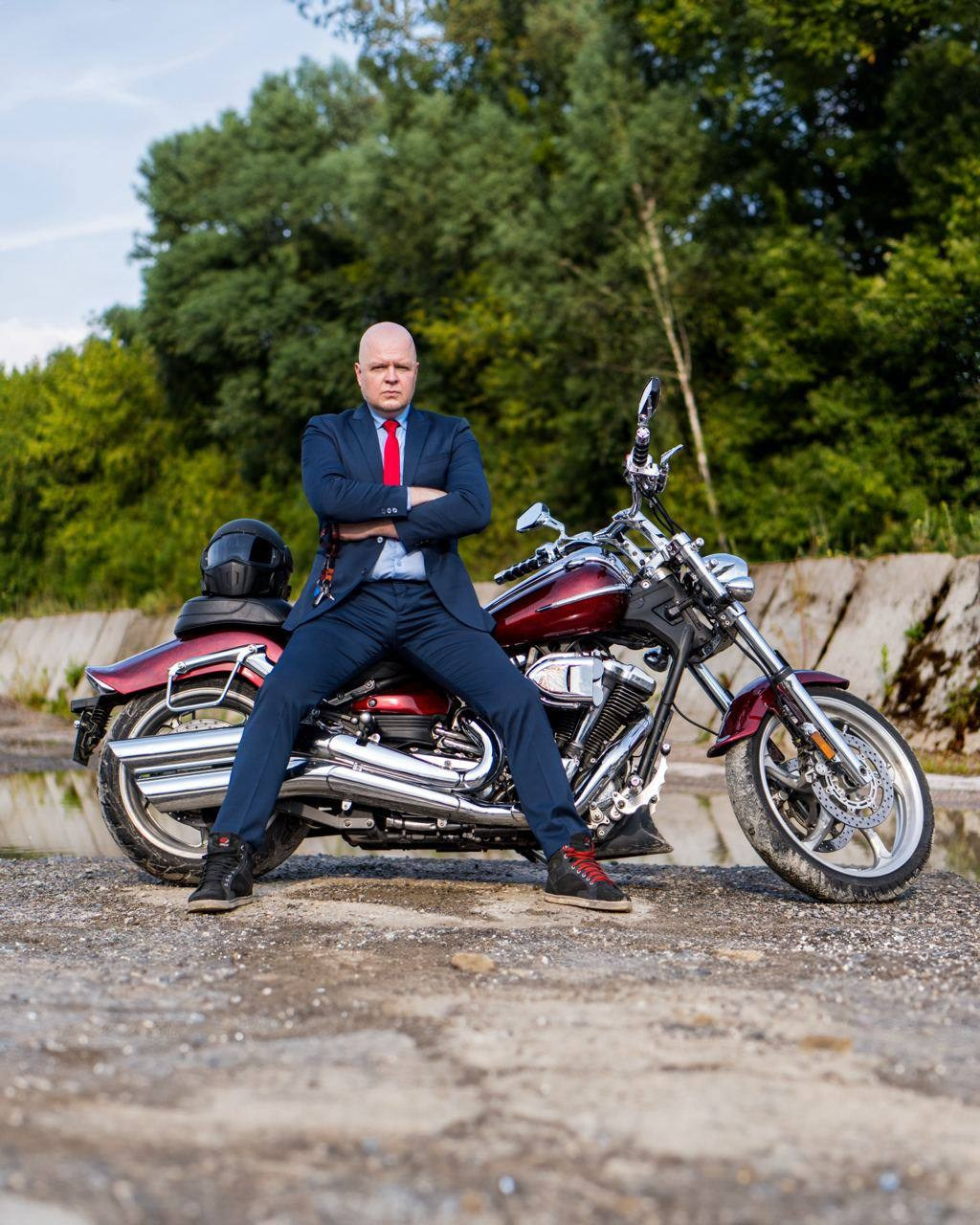 серьезный мужчина в пиджаке сидит на чоппере, скрестив руки на груди