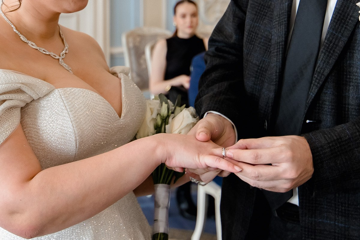Жених надевает кольцо невесте в зале регистраций в ЗАГСе на фурштатской СПб. Крупный план. Горизонтальный кадр