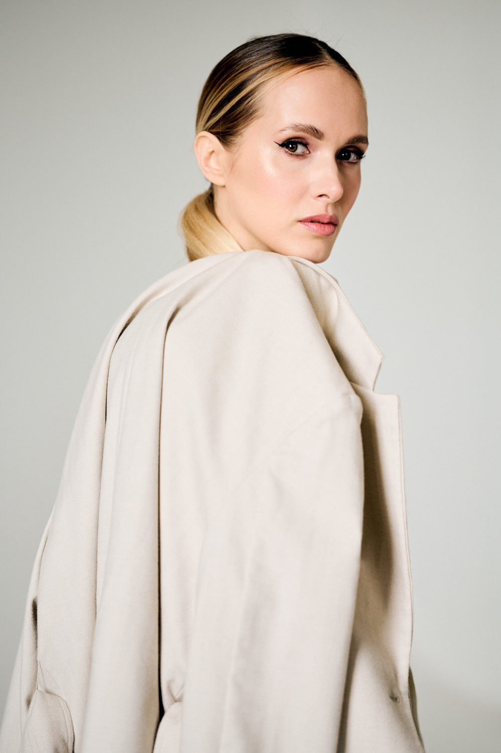 портрет молодой женщины в светлом пиджаке, наброшенном на плечи, смотрящей в полоборота