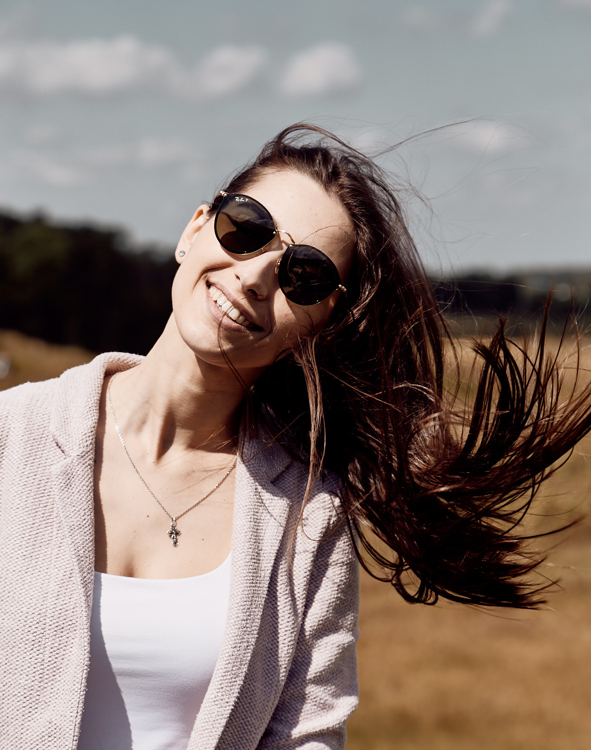 портрет молодой женщины в светлой футболке с чёрными распущенными волосами на фоне природы или неба