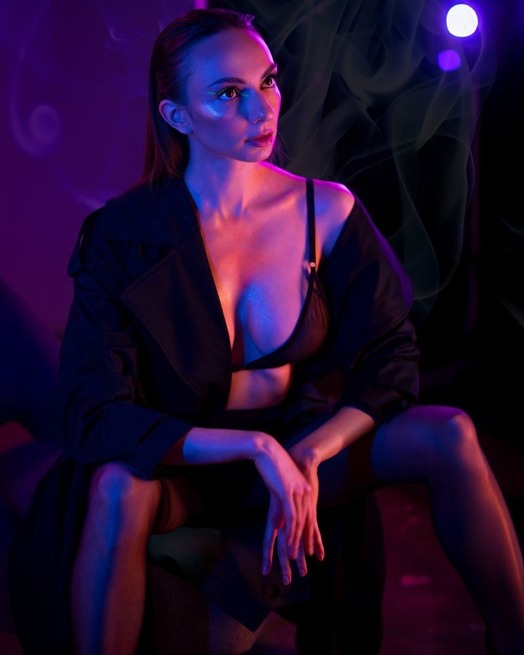 девушка в колготках и пиджаке сидит в неоновом освещении