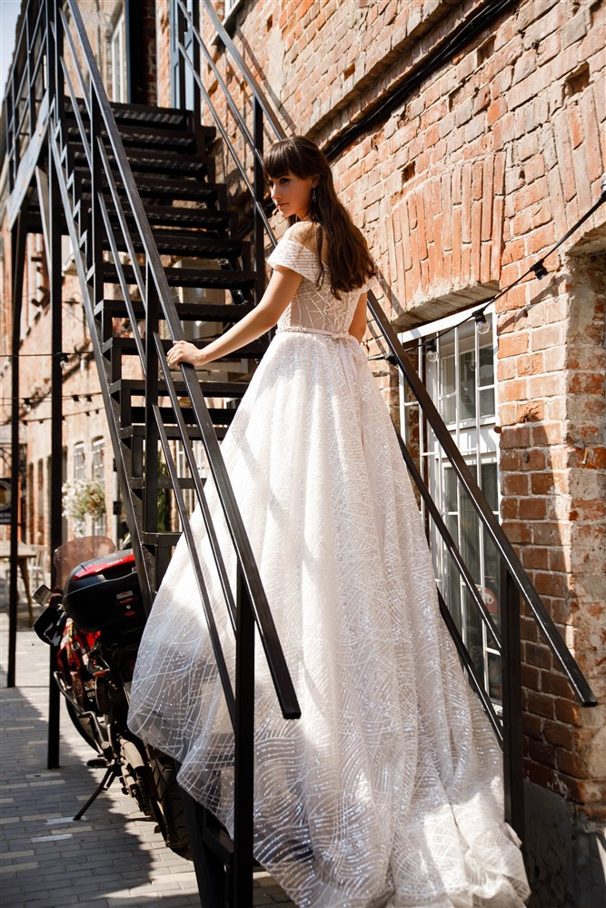 Невеста поднимается по лестнице. Свадебное платье со шлейфом.