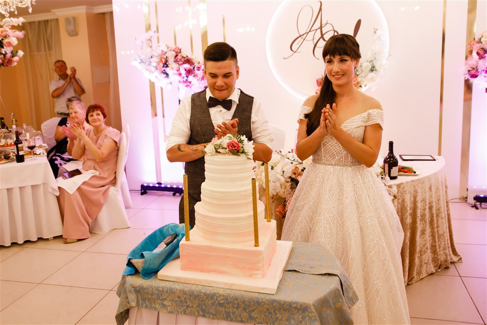 Жених и невеста любуются свадебным тортом.