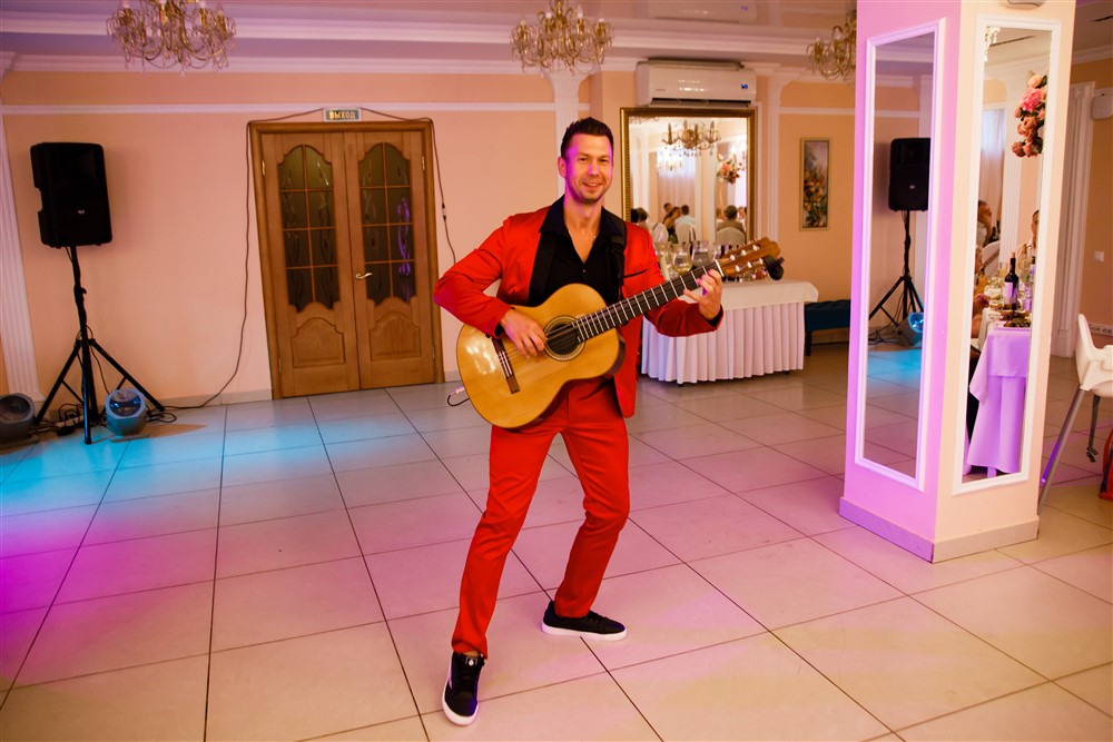 Гитарист исполняет музыкальную композицию на свадьбе.