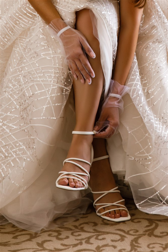 Сборы невесты, свадебное утро. Невеста надевает свадебные туфли.