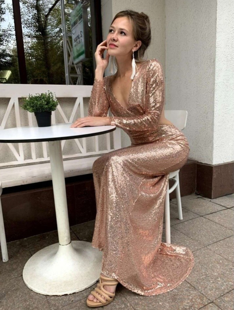 Девушка в золотистом платье с открытой спиной облегающее силуэтное сидит