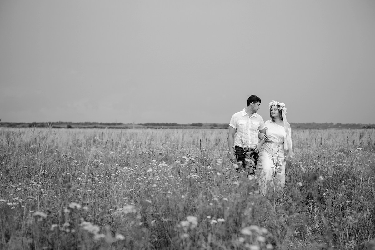 Жених и невеста в необычной одежде и стоят в поле