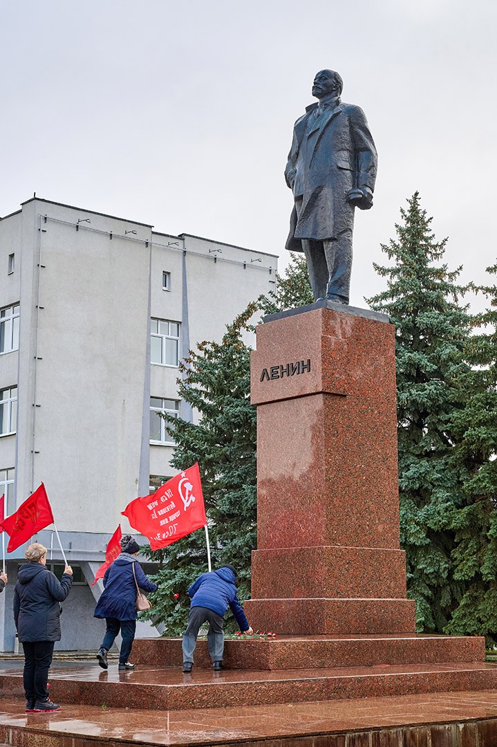 Люди несут цветы к памятнику Лениа