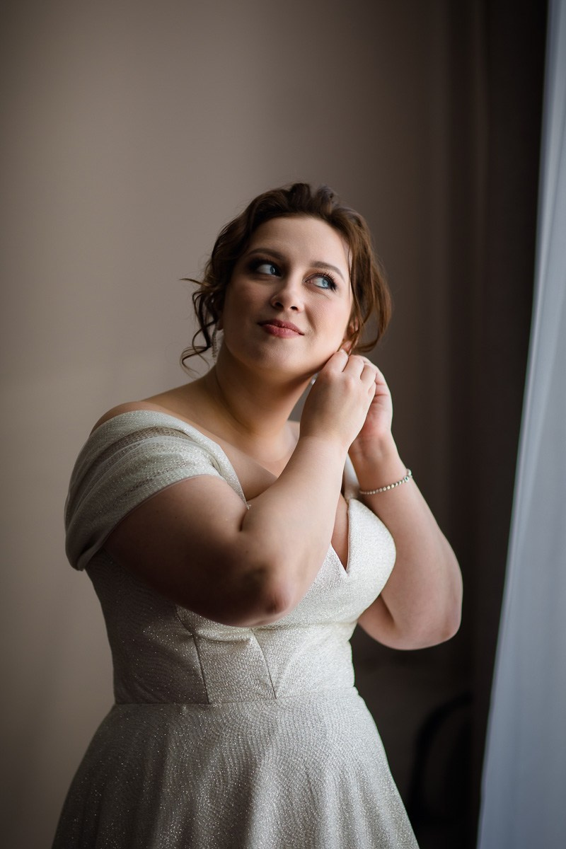 Невеста у окна надевает серёжку