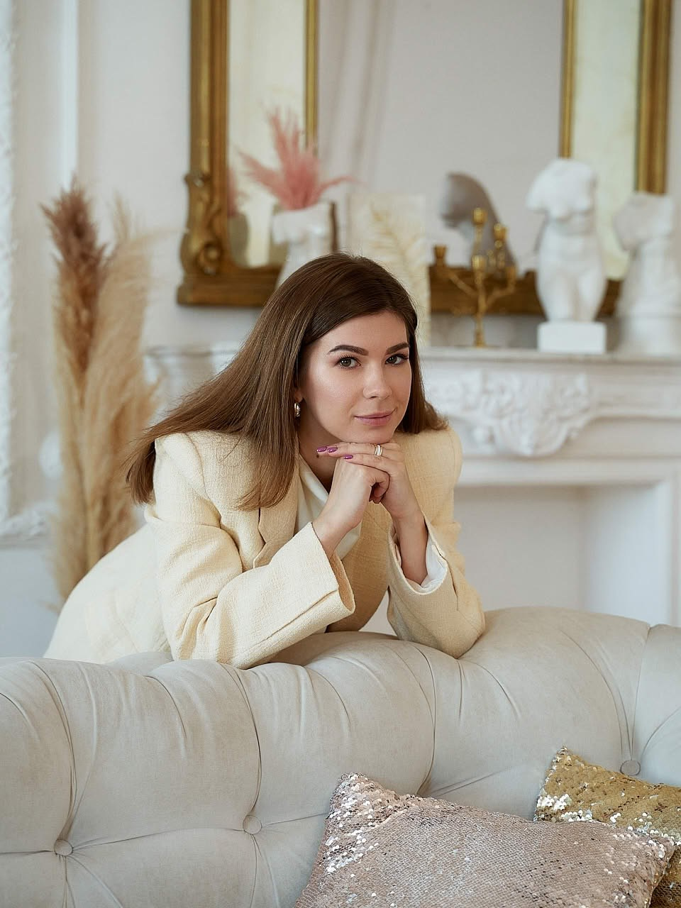 Индивидуальная фотосессия Санкт-Петербург — девушка в кремовом жакете опирается на светлый диван в классическом интерьере, мягкий фокус
