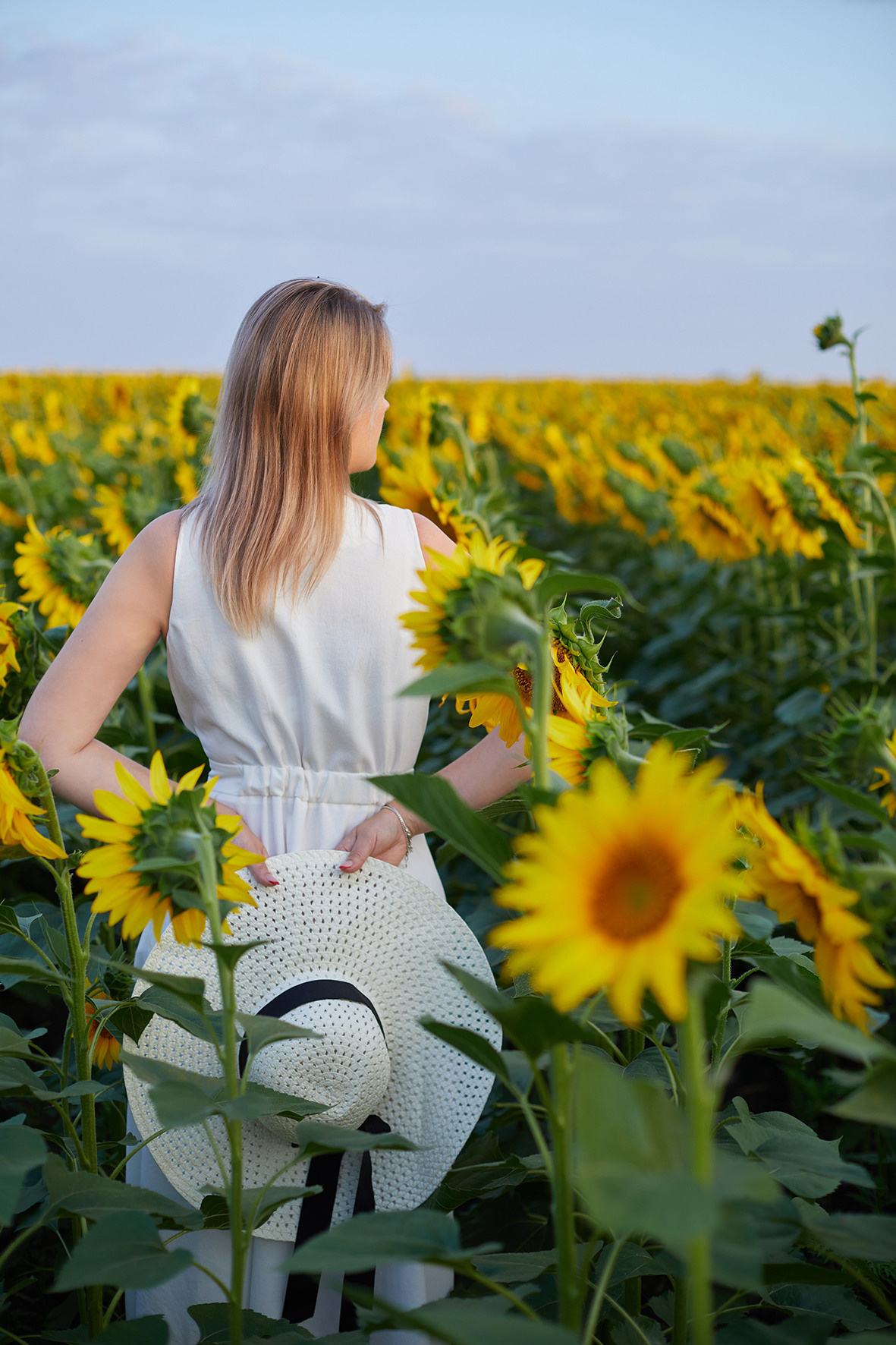 Девушка блондинка белом платье и соломенной шляпой в поле подсолнухов. Фотограф. Тимашевск. Краснодарский край.