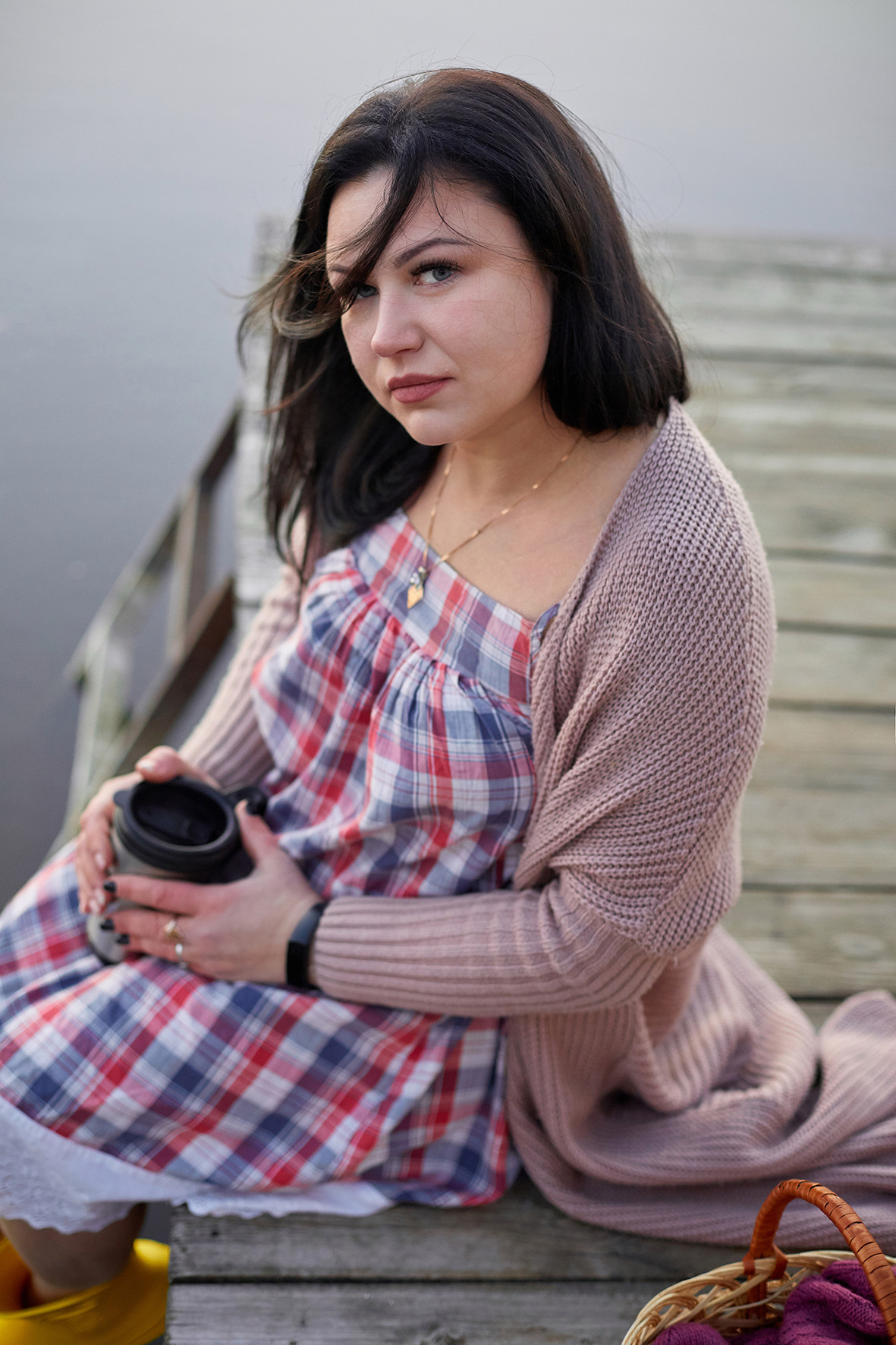 Портрет девушки на реке на закате. Девушка в вязаном кардигане и желтых резиновых сапожках на берегу реки на деревянном пирсе пьет кофе из термоса. Фотограф. Тимашевск. Кубань. Краснодарский край. 