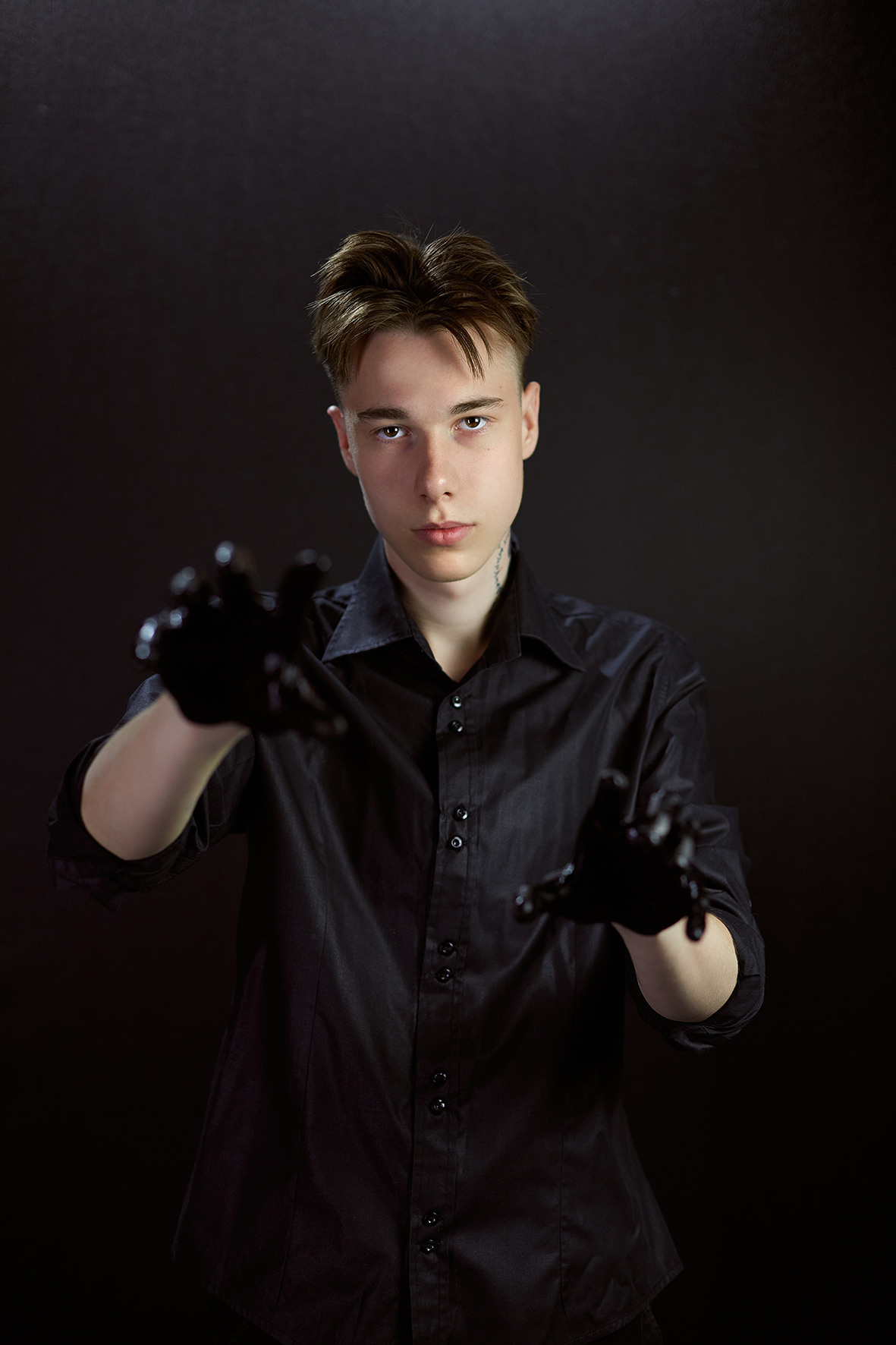 Студийный портрет парня на черном фоне в черной рубашке с руками в черной краске. Фотограф. Тимашевск. Кубань. Краснодарский край.