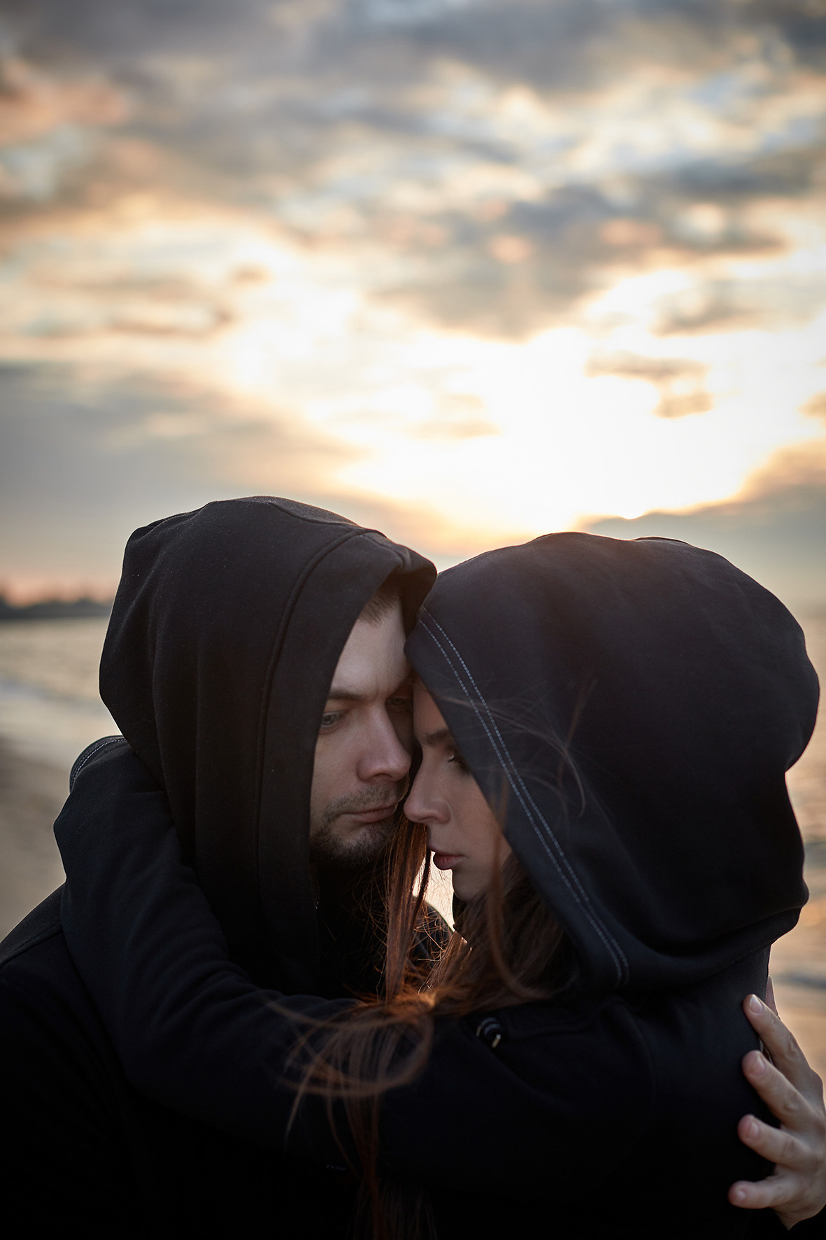 Лавстори на берегу моря во время заката. Море зимой. Парень и девушка в черной одежде обнимаются на берегу моря на закате. Приморско-Ахтарск. Фотограф. Тимашевск. Кубань. Краснодарский край.