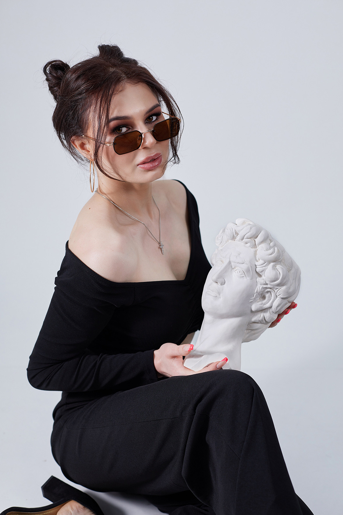 Студийный портрет красивой девушки в черной одежде и солнечных очках. Стильная девушка на белом фоне с гипсовой статуэткой в руках. Фотограф. Тимашевск. Кубань. Краснодарский край.