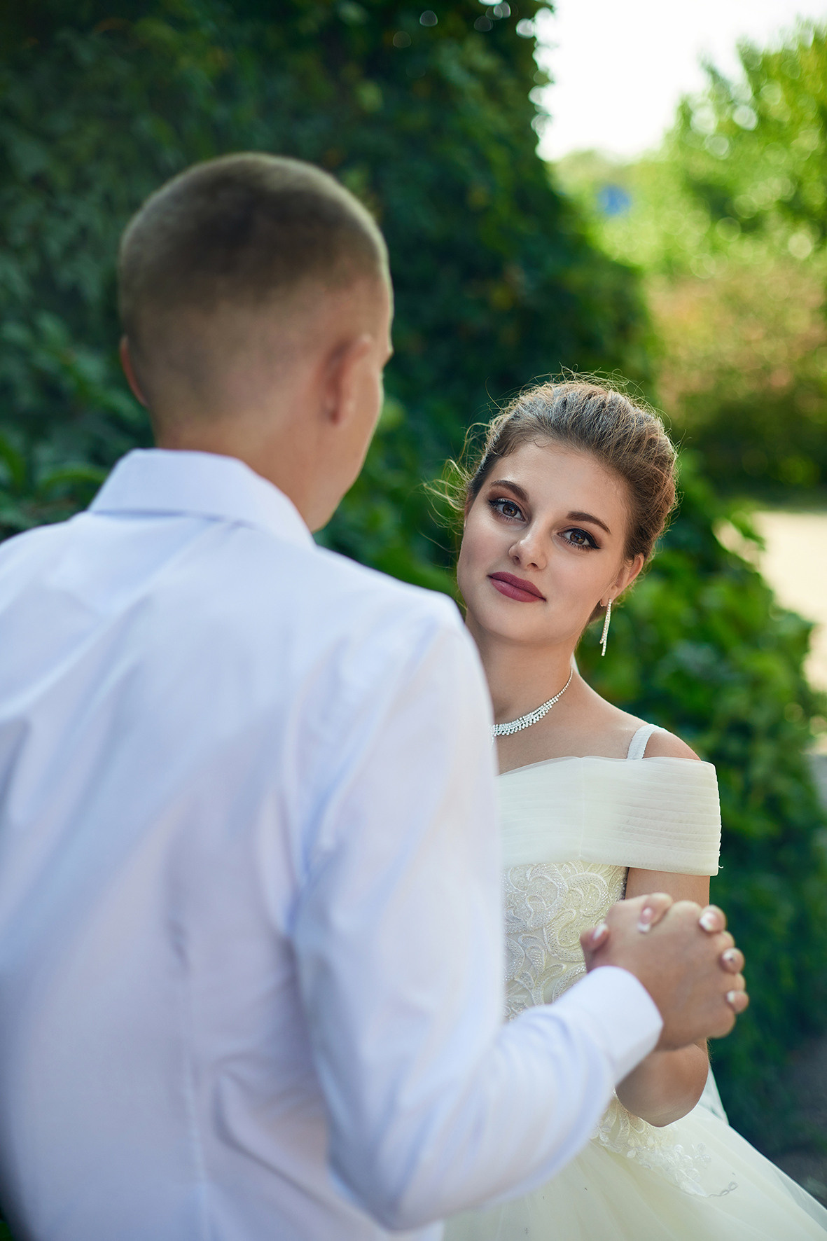 Невеста смотрит из-за плеча жениха. Невеста и жених в парке. Фотограф. Кубань. Краснодарский край. Тимашевск.