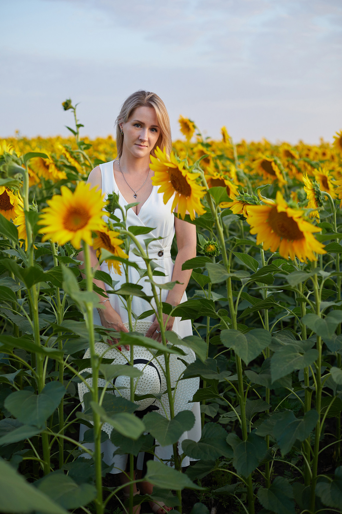 Девушка блондинка белом платье и соломенной шляпой в поле подсолнухов. Фотограф. Тимашевск. Краснодарский край.