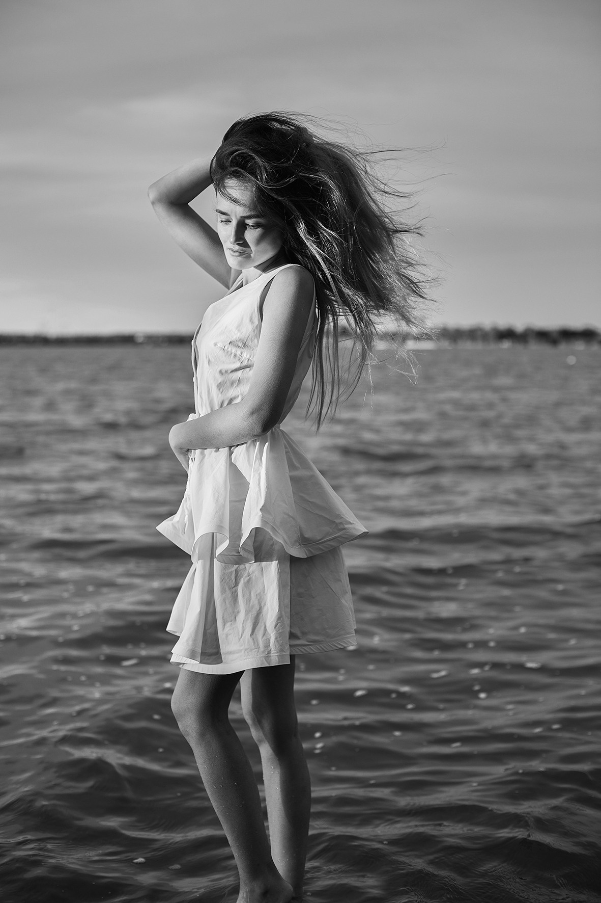 Девушка в белом коротком платье идет по воде. Река. Ветер развевает волосы. Фотограф. Тимашевск. Кубань. Краснодарский край.