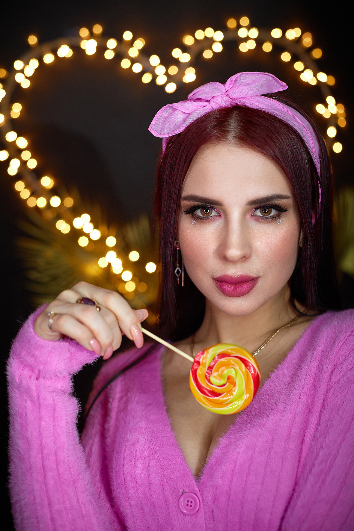 Студийный портрет девушки в розовой кофточке и с розовым платком на голове с карамельным леденцом в руках. Сердце из светодиодов на черном фоне. Фотограф. Тимашевск. Кубань. Краснодарский край.