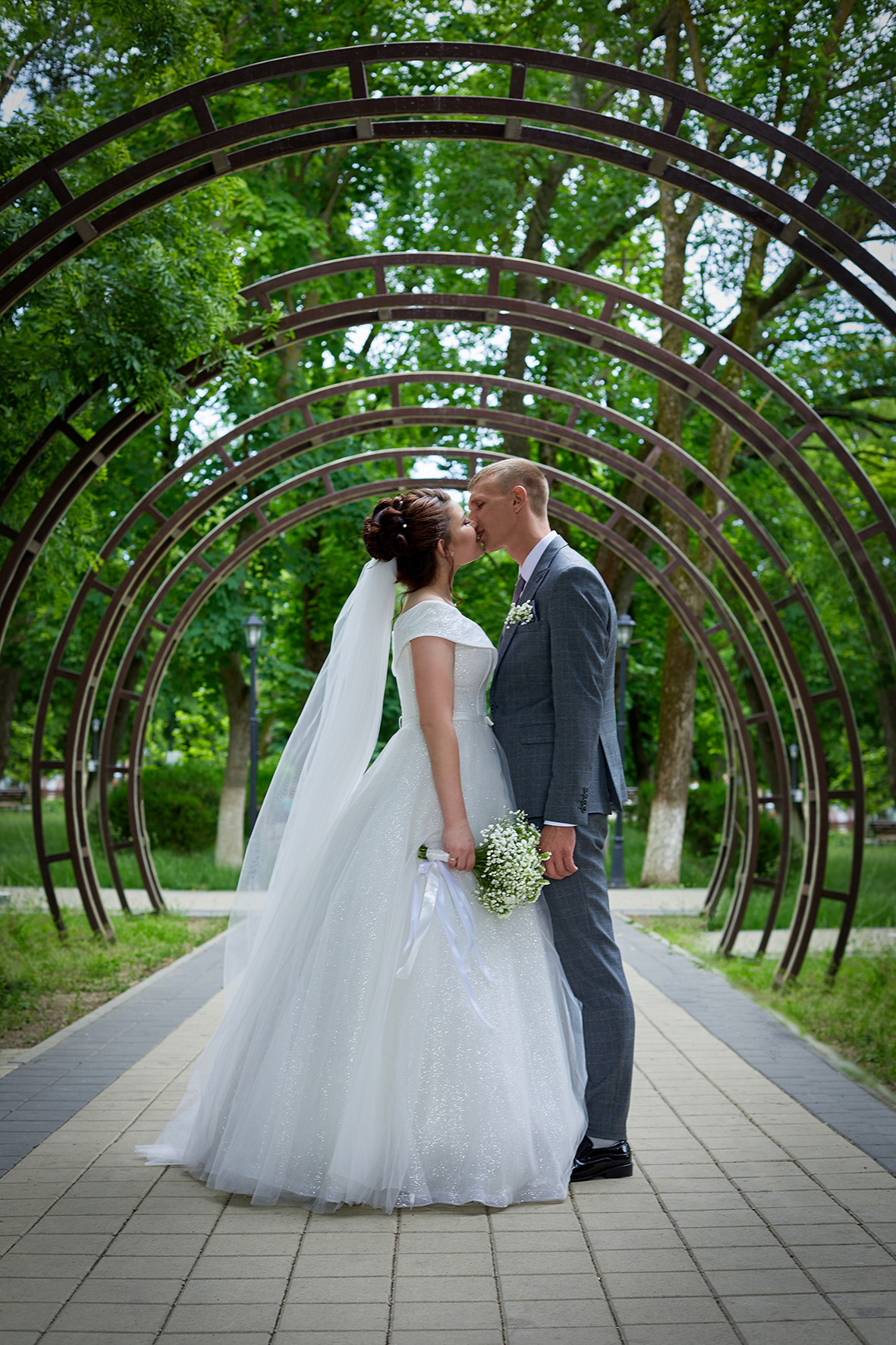 Жених и невеста целуются в арочном пролете в городском парке Приморско-Ахтарска. Приморско-Ахтарск. Фотограф. Тимашевск. Кубань. Краснодарский край.