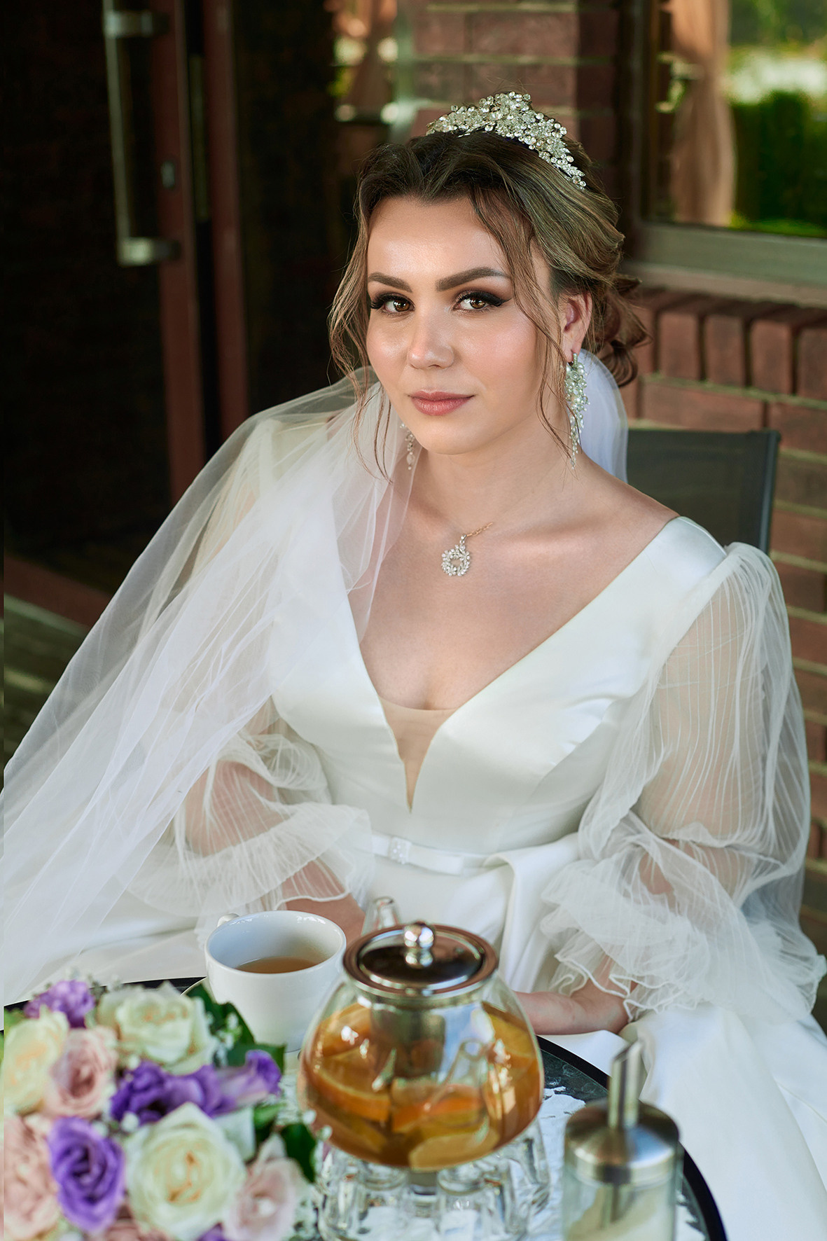 Невеста с белом платье сидит на террасе летнего кафе с чаем на столике. Фотограф. Тимашевск. Кубань. Краснодарский край.