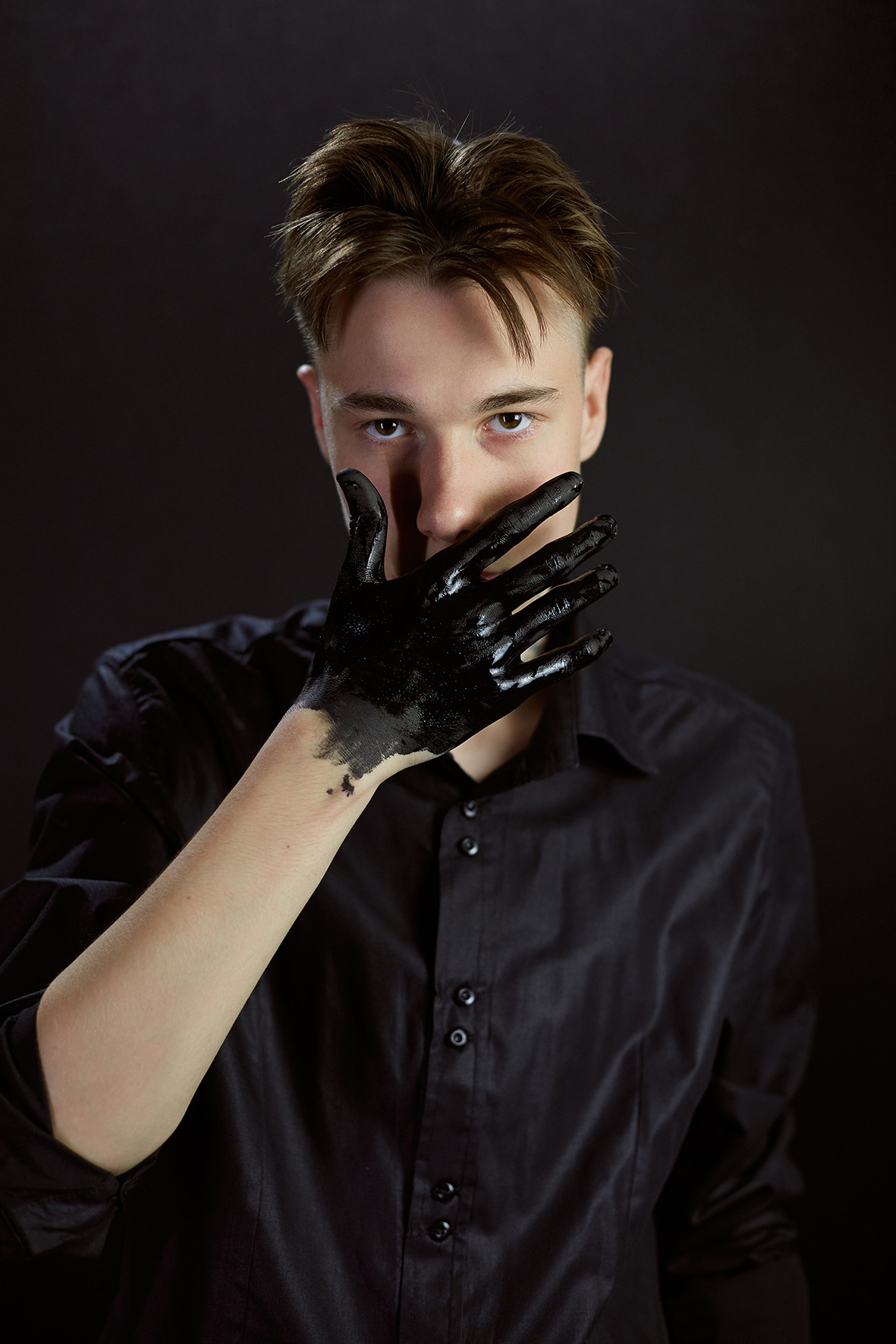 Студийный портрет парня на черном фоне в черной рубашке с руками в черной краске. Фотограф. Тимашевск. Кубань. Краснодарский край.