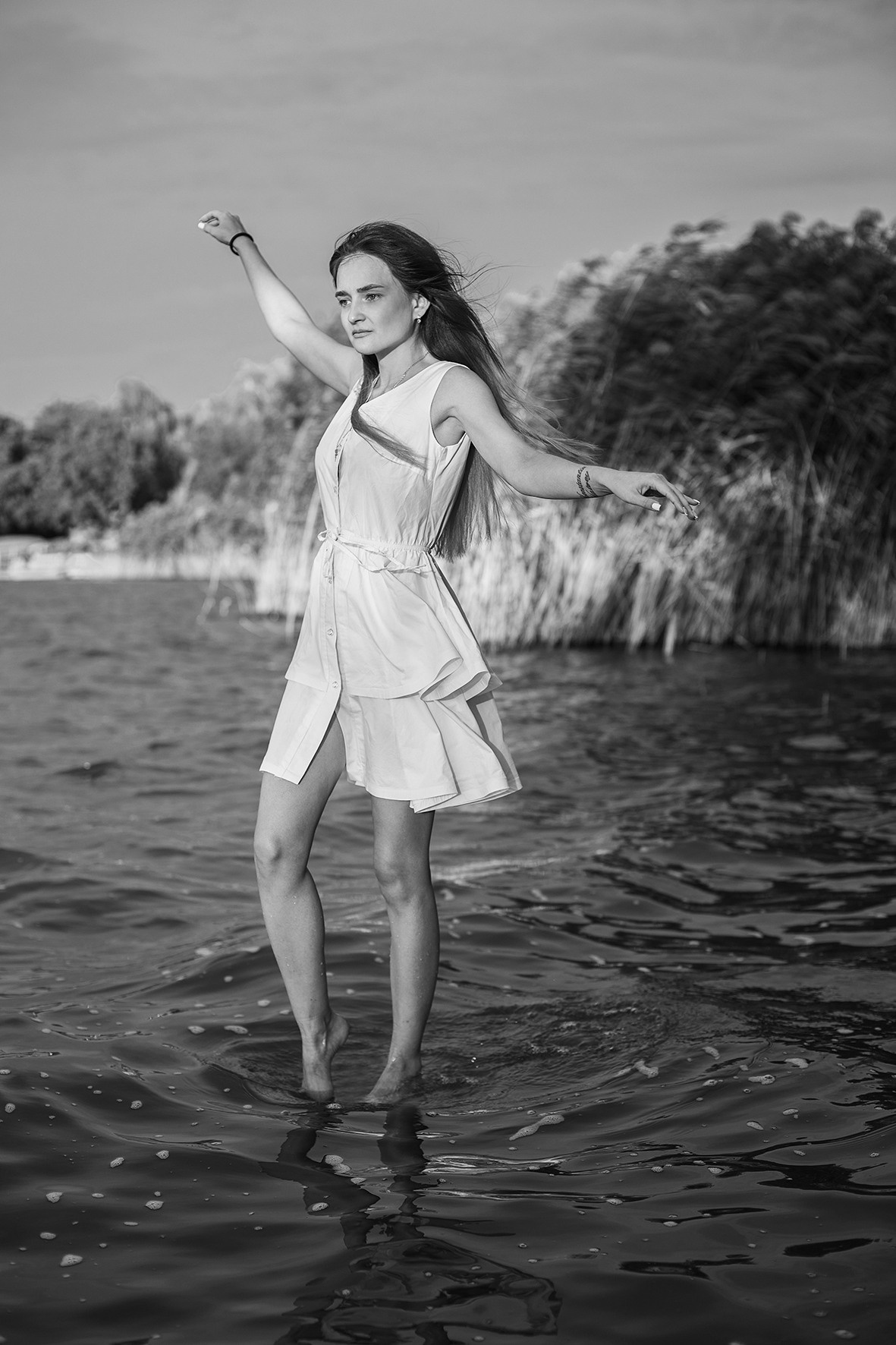 Девушка в белом коротком платье идет по воде. Река. Ветер развевает волосы. Фотограф. Тимашевск. Кубань. Краснодарский край.