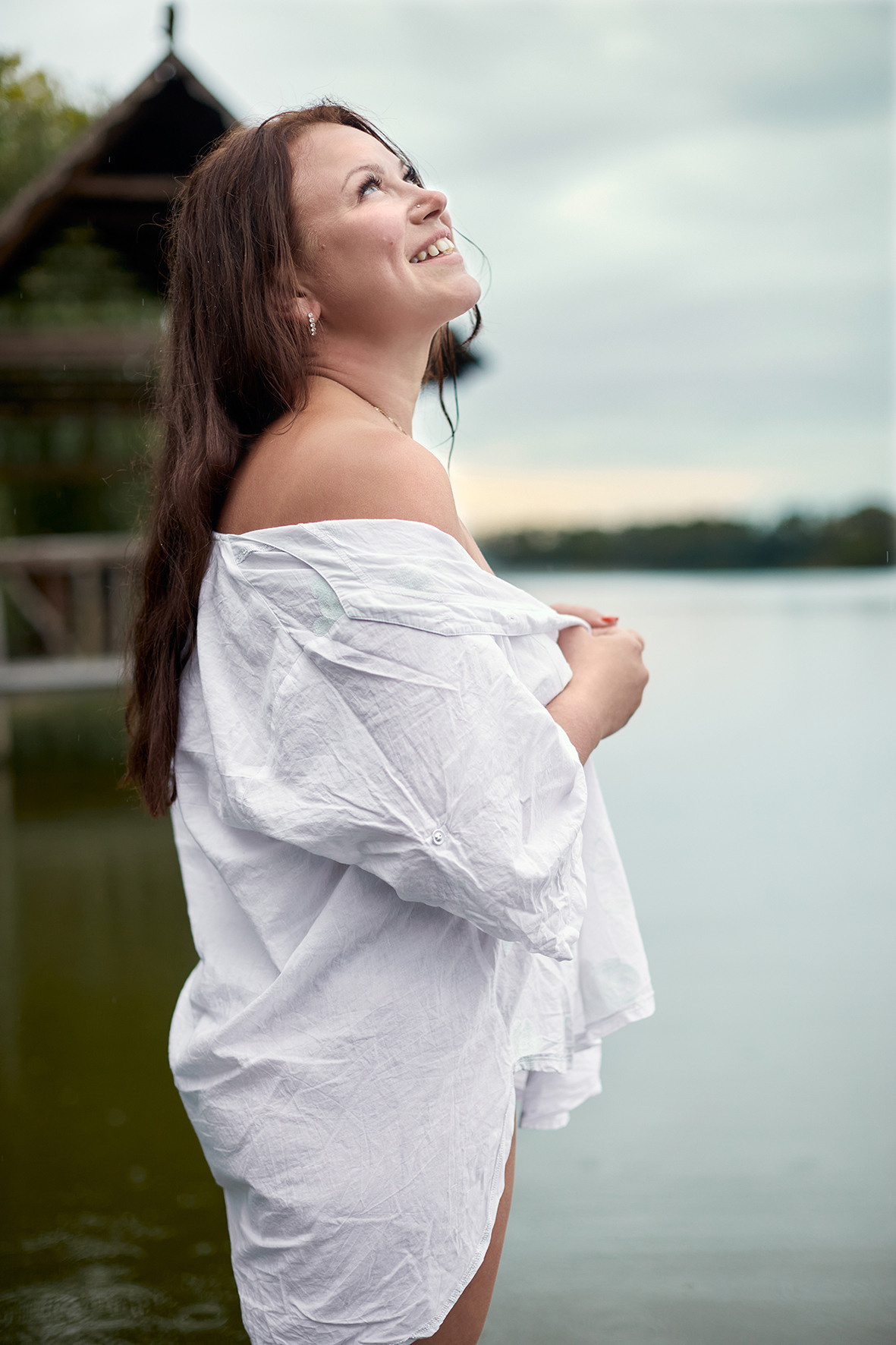 Девушка в белой рубашке стоит на реке на фоне деревянного домика. Фотограф. Тимашевск. Краснодарский край. Кубань.